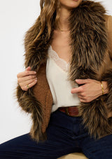 [Color: Sand] A detail image of a brunette model wearing a faux fur trimmed jacket with a collar, side pockets , and a sherpa lining. Styled with a dark wash denim and brown belt.