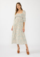 [Color: Dusty Sage/Natural] A front facing image of a brunette model wearing a green floral maxi dress with a mocked bust, three quarter sleeves, and a square neckline. 