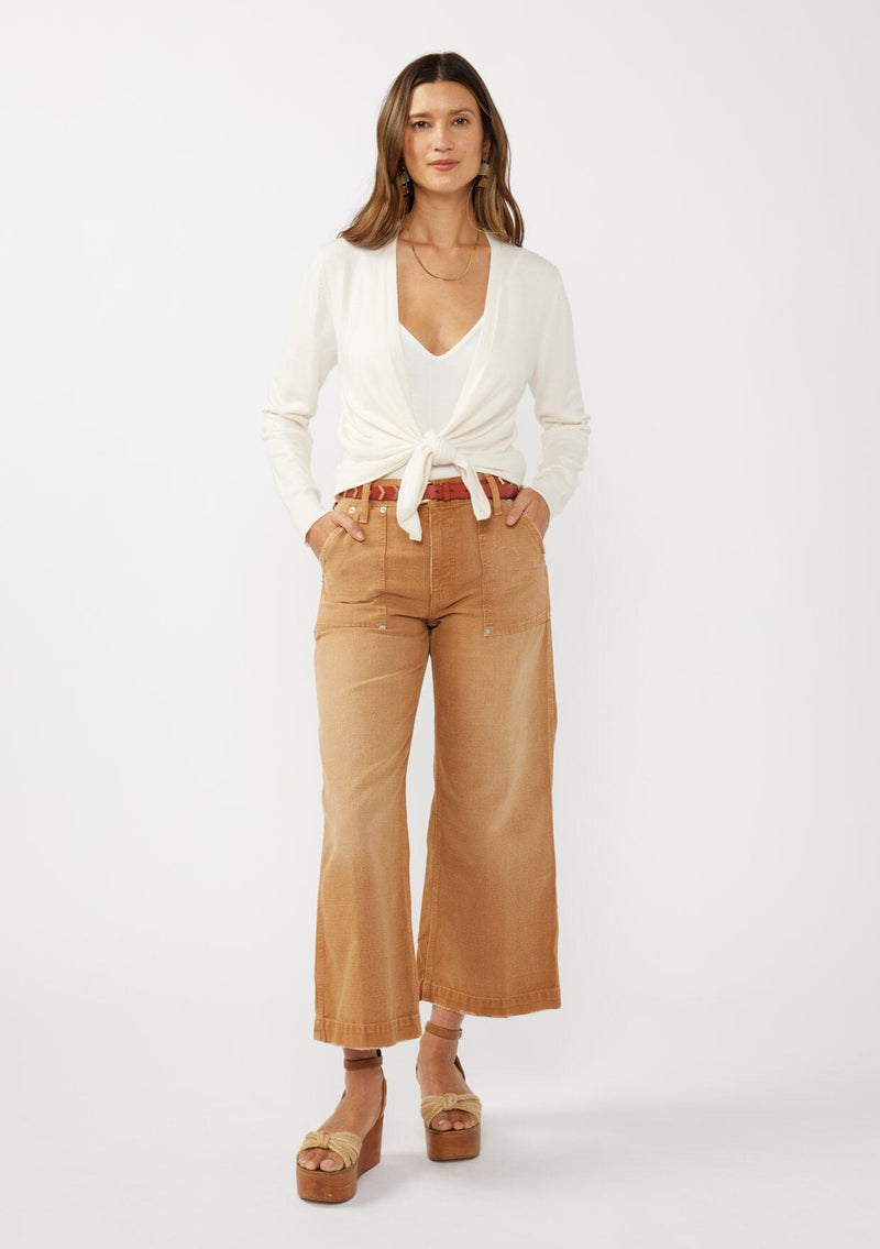 [Color: Off White] A front facing image of a brunette model wearing an off white solid knit sweater with a wrap front and side button closures. A soft versatile sweater, perfect for spring styling. 