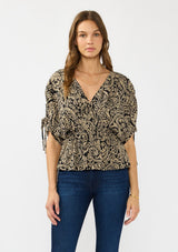[Color: Black/Natural] A front facing image of a brunette model wearing a black and beige paisley print top with ruched sleeves, a v neckline, and an elastic peplum waist. 