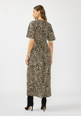 [Color: Black/Natural] A back facing image of a brunette model wearing a black and beige paisley maxi dress with short sleeves, a deep v neckline, and a side slit. 