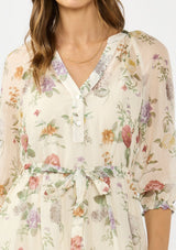 [Color: Ivory/Rosewood] A detail image of a brunette model wearing an ivory floral midi dress with a waist belt, three quarter sleeves, and a v neckline. 
