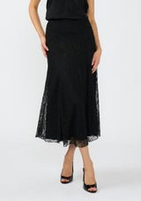 [Color: Black] A front facing image of a model wearing a black lace maxi skirt with black patent pumps. 