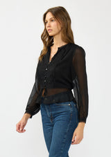 [Color: Black] A side facing image of a brunette model wearing a sheer black top with a front lace accent, button front, long sleeves, and a tie front waist detail. 