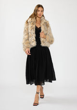 [Color: Leopard] A front facing image of a brunette model wearing a leopard faux fur coat over a black lace cami and maxi skirt. 