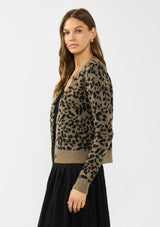 [Color: Brown] A side facing image of a brunette model wearing a brown leopard print cardigan with a button front, round neckline, and a contrast ribbed border. 