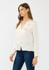 [Color: Eggshell] A side facing image of a brunette model wearing a white satin blouse with a collar, v-neckline, button front, and long sleeves. 