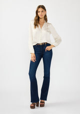 [Color: Eggshell] A front facing image of a brunette model wearing a white satin blouse with a collar, v-neckline, button front, and long sleeves. Tucked into a dark wash denim. 