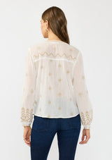 [Color: White/Sand] A back facing image of a brunette model wearing a white bohemian embroidered blouse with a button front. Styled with blue denim bottoms.