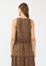 [Color: Brown] A back facing image of a brunette model wearing a brown crop tank top with tonal embroidery and a round neckline. Styled with a matching midi skirt. 