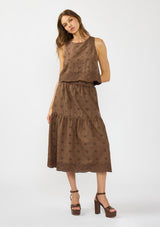 [Color: Brown] A front facing image of a brunette model wearing a brown crop tank top with tonal embroidery and a round neckline. Styled with a matching midi skirt. 