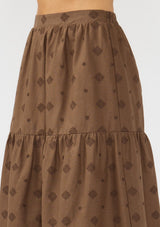 [Color: Brown] A detail image of a brunette model wearing a brown embroidered midi skirt.