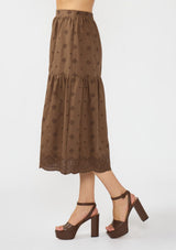 [Color: Brown] A side facing image of a brown embroidered midi skirt. 