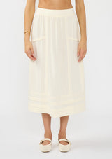 [Color: Natural] A front facing image of a model wearing an off white midi skirt with lace trims and pintucks. 
