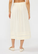 [Color: Natural] A back facing image of a model wearing an off white midi skirt with lace trims and pintucks. 
