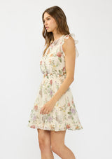 [Color: Ivory/Rosewood] A side facing image of a brunette model wearing an ivory floral mini dress with flutter cap sleeves, a button front, smocked waist, and a tiered skirt with ruffle trims.