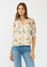 [Color: Ivory/Rosewood] A front facing image of a brunette model wearing an ivory floral print top with puff sleeves, smocked cuffs, smocked neck, and a button front.