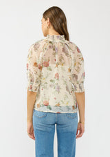 [Color: Ivory/Rosewood] A back facing image of a brunette model wearing an ivory floral print top with puff sleeves, smocked cuffs, smocked neck, and a button front.