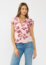 [Color: Coral/Wine] A front facing image of a brunette model wearing a pink and wine floral print top with a ruched center, short flutter sleeves, and a v neckline. 