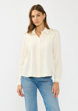 [Color: Natural] A front facing image of a brunette model wearing an off white lace shirt with a collared neck and button front. 
