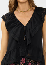 [Color: Black] A detail image of a brunette model wearing a black flutter sleeve top with lace trims, a button front, and a ruffle trimmed hem.