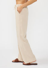 [Color: Sand] A side facing image of a tencel blend beige drawstring pant with an elastic waistband and side pockets. 