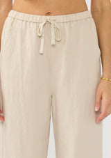 [Color: Sand] A detail image of a tencel blend beige drawstring pant with an elastic waistband and side pockets. 