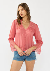 [Color: Dark Rose] A front facing image of a brunette model wearing a pink bohemian lace trim blouse with a v neckline and button front. 