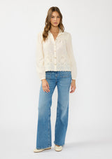 [Color: Cream/Natural] A front facing image of a brunette model wearing an off white embroidered shirt with a collared neck and button front. 