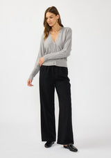 [Color: Heather Grey] A front facing image of a brunette model wearing a grey button front cardigan with long dolman sleeves, a v neckline, and rib trims. 