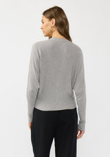 [Color: Heather Grey] A back facing image of a brunette model wearing a grey button front cardigan with long dolman sleeves, a v neckline, and rib trims. 