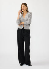 [Color: Black] A front facing image of a brunette model wearing a black tencel blend drawstring pant with an elastic waistband and side pockets. Styles with a grey cardigan.