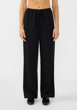 [Color: Black] A front facing image of a model wearing a black tencel blend drawstring pant with an elastic waistband and side pockets. 