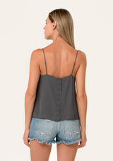 [Color: Pewter] A back facing image of a blonde model wearing a grey bohemian camisole with adjustable spaghetti straps, a scoop neckline, a button up back, and lace detail.