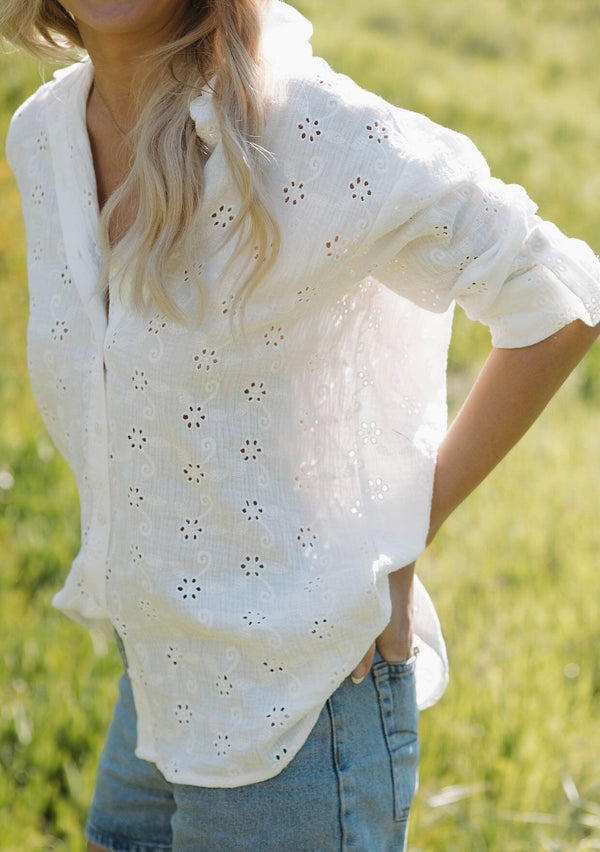 [Color: White] A front facing image of a brunette model wearing a classic white bohemian shirt crafted in embroidered eyelet cotton. With long sleeves, a classic collared neckline, and a button front.