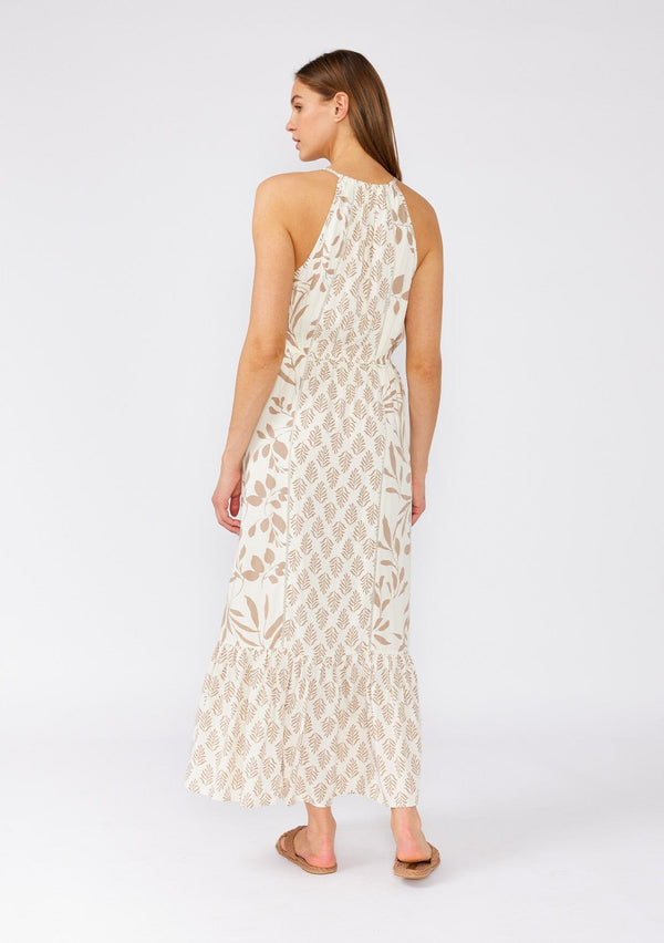 [Color: Latte/Natural] A back facing image of a brunette model wearing an dreamy bohemian maxi dress in an ivory and brown print. With spaghetti straps, a high neckline, a front keyhole detail, a tie neckline, an elastic waist, a tiered flowy skirt, and ladder stitch details throughout. 