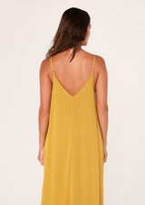 [Color: Mustard] A back facing image of a brunette model wearing a mustard yellow harem maxi dress. This billowy maxi tank top dress features a deep v neckline, adjustable spaghetti straps, and a cocoon fit.