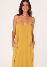 [Color: Mustard] A close up front facing image of a brunette model wearing a mustard yellow harem maxi dress. This billowy maxi tank top dress features a deep v neckline, adjustable spaghetti straps, and a cocoon fit.