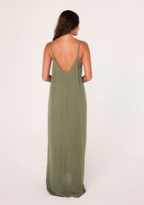 [Color: Leaf Green] A back facing image of a brunette model wearing a leaf green harem maxi dress. This billowy maxi tank top dress features a deep v neckline, adjustable spaghetti straps, and a cocoon fit.