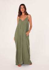 [Color: Leaf Green] A front facing image of a brunette model wearing a leaf green harem maxi dress. This billowy maxi tank top dress features a deep v neckline, adjustable spaghetti straps, and a cocoon fit.