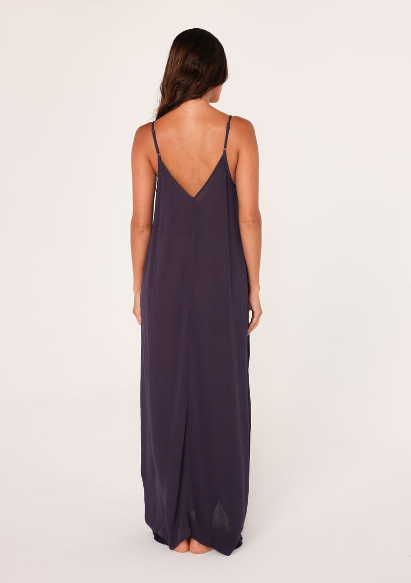 [Color: Dark Purple] A back facing image of a brunette model wearing a dark purple harem maxi dress. This billowy maxi tank top dress features a deep v neckline, adjustable spaghetti straps, and a cocoon fit.