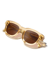 [Color: Butter]: Thick sunglasses with a caramel lens in a light gold tone acetate frame. Designed in Italian cellulose acetate with stainless steel temples.