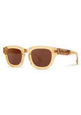 [Color: Butter]: Thick sunglasses with a caramel lens in a light gold tone acetate frame. Designed in Italian cellulose acetate with stainless steel temples.