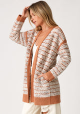 [Color: Mocha/Natural] A side facing image of a blonde model wearing a bohemian fall cardigan in a speckled loop knit stripe. With long sleeves, side pockets, an open front, and contrast brown ribbed trim. 