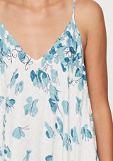 [Color: Hazel Teal/Vanilla] A detail image of a brunette model wearing a bohemian white and blue butterfly print maxi dress with a v neckline and adjustable spaghetti straps. 