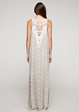 [Color: Aqua/Peach] A brunette model wearing a sleeveless maxi dress with a an abstract print, a white chevron pattern and a crochet back panel.