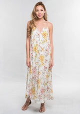 [Color: Strawberry/Gold] A front facing image of a brunette model wearing a pink and yellow floral sleeveless halter maxi dress with a relaxed, flowy silhouette and tassel ties. Styled with brown strappy sandals. 