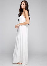 [Color: Off White] A side facing image of a brunette model wearing a white maxi dress with a relaxed fit, scoop neckline with crochet ball trim, and adjustable spaghetti straps. 