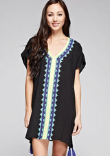 [Color: Black] A front facing image of a brunette model wearing a black embroidered tunic with embroidery and a tassel accent at the hem.