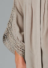 [Color: Taupe] A detail image of a brunette model wearing a bohemian v-neck blouse with lace crochet detail at the sleeve.
